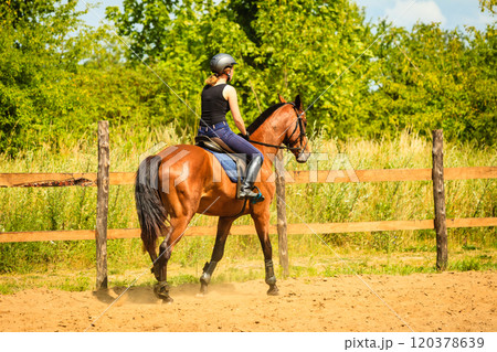 Jockey girl doing horse riding on countryside meadow 120378639