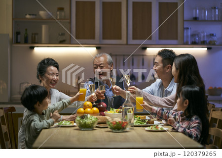 three generation asian family toasting while having dinner together three generation asian family toasting while having dinner together 120379265
