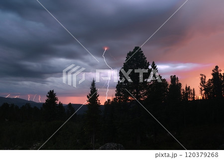 Powerful lightning strikes illuminate a stormy sky at sunset in a mountainous region Powerful lightning strikes illuminate a stormy sky at sunset in a mountainous region 120379268