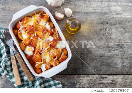 Gnocchi Alla Sorrentina with tomato sauce and oven-baked melted mozzarella cheese on wooden table. Gnocchi Alla Sorrentina with tomato sauce and oven-baked melted mozzarella cheese on wooden table. 120379507