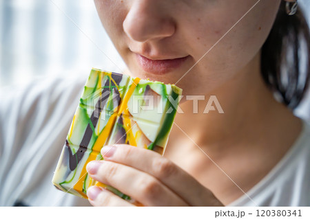 Woman eating trend Dubai white chocolate with pistachio paste and kataifi dough. Confectionery handmade sweets at home in the kitchen.  120380341