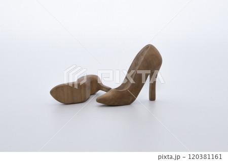 Pair of women's shoes made from wood. A beautiful high-heeled wooden shoes against white background. Handmade shoes for use in female concept Pair of women's shoes made from wood. A beautiful high-heeled wooden shoes against white background. Handmade shoes for use in female concept 120381161