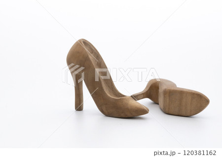 Pair of women's shoes made from wood. A beautiful high-heeled wooden shoes against white background. Handmade shoes for use in female concept Pair of women's shoes made from wood. A beautiful high-heeled wooden shoes against white background. Handmade shoes for use in female concept 120381162