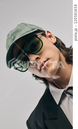 Close-up portrait of handsome young guy wearing style accessories, green baseball cap, and oversized green sunglasses 120381658
