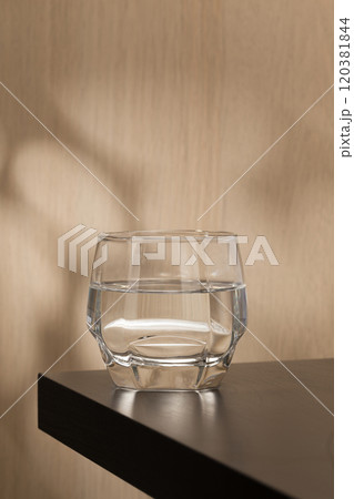 A clear glass of drinking water sits on a wooden table. A clear glass of drinking water sits on a wooden table. 120381844