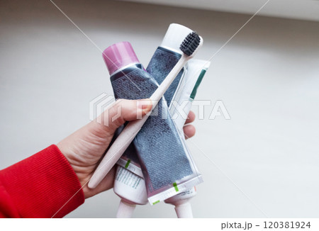 Woman holds many tubes of oral hygiene products in her hand. Using natural toothpaste with safe sweeteners and eco-friendly ingredients 120381924