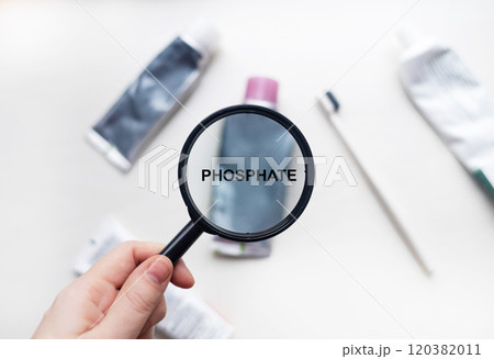 Phosphate in natural toothpaste. Magnifying glass is directed at a tube with a list of ingredients of a safe product. Safe toothpaste composition 120382011