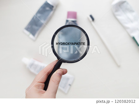 Hydroxyapatite in natural toothpaste. Magnifying glass is directed at a tube with a list of ingredients of a safe product. Safe toothpaste composition 120382012