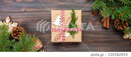 Christmas background with fir tree and gift box on wooden table. Top view with copy space for your design Christmas background with fir tree and gift box on wooden table. Top view with copy space for your design 120382654