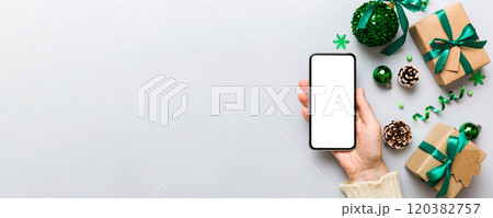 christmas mockup with space for text. christmas advertising, app template. hand holding phone with empty screen on table background. Happy New Year and Xmas Flat lay christmas mockup with space for text. christmas advertising, app template. hand holding phone with empty screen on table background. Happy New Year and Xmas Flat lay 120382757