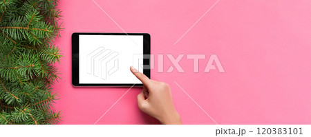 people and technology concept, close up of female hands pointing finger to tablet. blank screen on pink background, top view 120383101