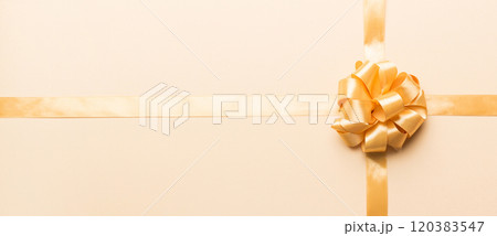 Top view of gold ribbon rolled and yellow bow isolated on colored background. Flat lay with copy space 120383547