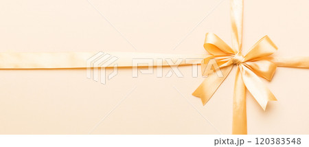 Top view of gold ribbon rolled and yellow bow isolated on colored background. Flat lay with copy space Top view of gold ribbon rolled and yellow bow isolated on colored background. Flat lay with copy space 120383548