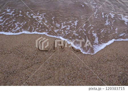 The beach with sea waves running on the sand and the word LIVE is drawn on the sand. Beautiful view on the waves The beach with sea waves running on the sand and the word LIVE is drawn on the sand. Beautiful view on the waves 120383715