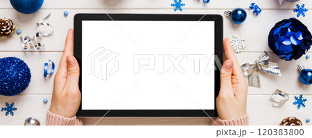 Christmas online shopping from home, female hands holding tablet pc with blank white display top view. woman hand holding tablet with blank screen, Christmas tree and gifts on background Christmas online shopping from home, female hands holding tablet pc with blank white display top view. woman hand holding tablet with blank screen, Christmas tree and gifts on background 120383800