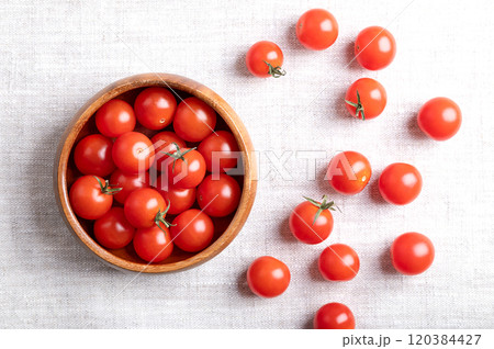 Small red cherry tomatoes in a wooden bowl on linen fabric, from above. Fresh, ripe, tiny and round cocktail tomatoes of the type Solanum lycopersicum var. cerasiforme, of juicy and sweet taste. Small red cherry tomatoes in a wooden bowl on linen fabric, from above. Fresh, ripe, tiny and round cocktail tomatoes of the type Solanum lycopersicum var. cerasiforme, of juicy and sweet taste. 120384427
