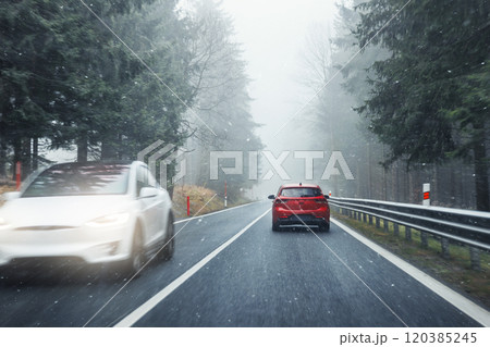 Scenic view nature park highway slippery mountain alpine road driving cars moving fast speed motion. Snowfall danger blizzard bad winter weather conditions. Cold snowy day snowstorm background 120385245