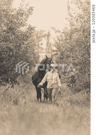 Western woman walking on green meadow with horse 120385469