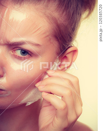 Woman removing facial peel off mask closeup Woman removing facial peel off mask closeup 120385720