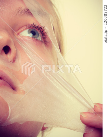 Woman removing facial peel off mask closeup 120385722