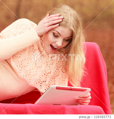 Woman in fall park with tablet browsing internet. 120385771