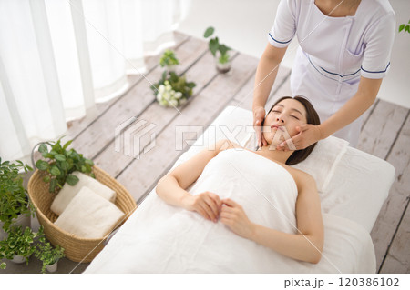 エステティシャンにマッサージを受ける女性 120386102
