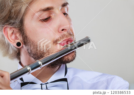 Male flutist playing his flute closeup Male flutist playing his flute closeup 120386533