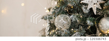 Banner close-up of a Christmas tree against a background of blurry garland lights. 120386743
