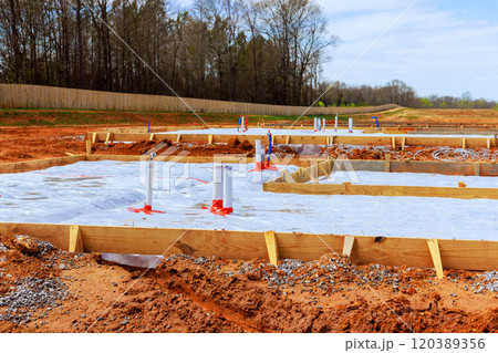 Construction worker prepare foundation of anew building wooden forms pipes are set up on plot of land 120389356