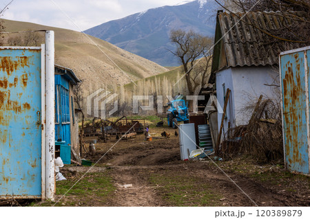 Poor rustic backyard with old blue tractor with dirt road between houses Poor rustic backyard with old blue tractor with dirt road between houses 120389879
