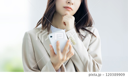 スマホを持って悩む女性・ビジネスウーマン スマホを持って悩む女性・ビジネスウーマン 120389909