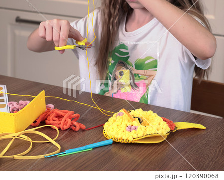 Teenage girl doing handcraft, sewing purse from threads. Hobby and creativity, useful pastime. Teenage girl doing handcraft, sewing purse from threads. Hobby and creativity, useful pastime. 120390068