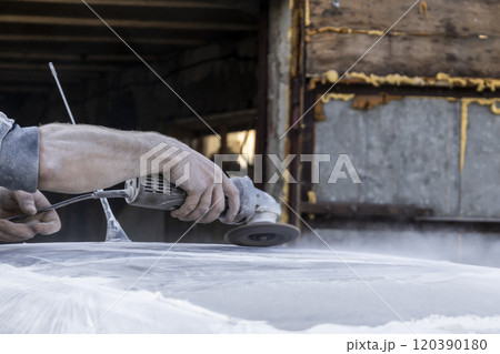 Hands of the auto repairman grinding roof of the car. 120390180