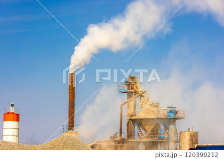 white steam rising up from pipe of small asphalt factory at day time with piles of gravel in a foreground white steam rising up from pipe of small asphalt factory at day time with piles of gravel in a foreground 120390212