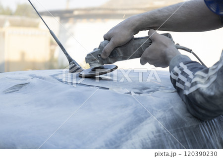 Hands of the auto repairman grinding roof of the car. Hands of the auto repairman grinding roof of the car. 120390230