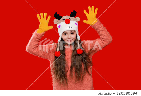 Winter child wardrobe. Teenage girl in Xmas hat isolated on red. Winter fashion for teenage style. Girl in knitted hat in winter season. Childhood lifestyle. Earflap fashion 120390594