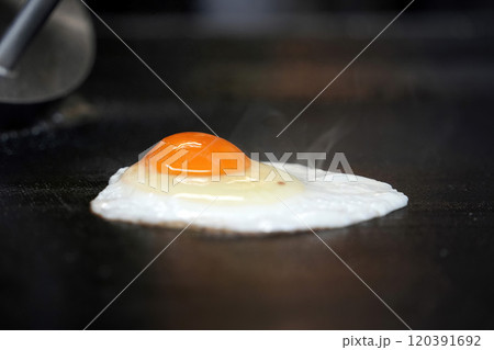 fried egg for Hamburger being prepared on a moving hot plate 120391692