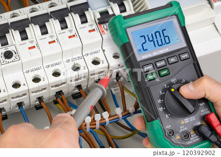 Electrician Testing Voltage in Circuit Breaker System with Multimeter 120392902