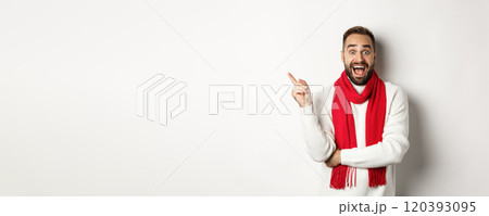 Christmas shopping and winter holidays concept. Surprised man pointing finger left, showing promo offer, standing over white background 120393095