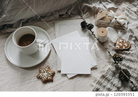Christmas stationery still life. Blank greeting crad, invitation mockup. Silk, velvet ribbons, gingerbread cookies. Cup of coffee, larch cones on table. Gift wrapping, craft concept. Flatlay, top 120393351
