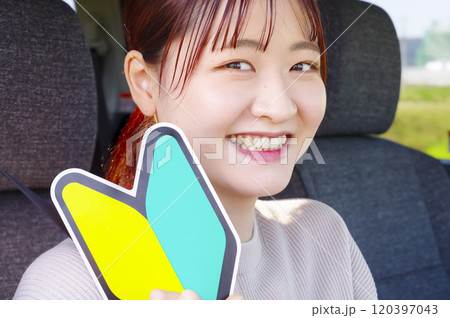 運転席で初心者マークを持つ笑顔の女性 運転席で初心者マークを持つ笑顔の女性 120397043