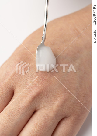 スパチュラで保湿クリームを取り手の甲に乗せる 120397498