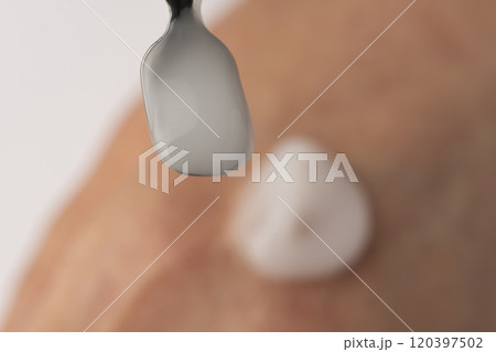 スパチュラで保湿クリームを取り手の甲に乗せる スパチュラで保湿クリームを取り手の甲に乗せる 120397502