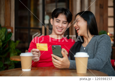 A lovely couple enjoys a relaxing moment together at a coffee shop, shopping online on a smartphone. 120398157