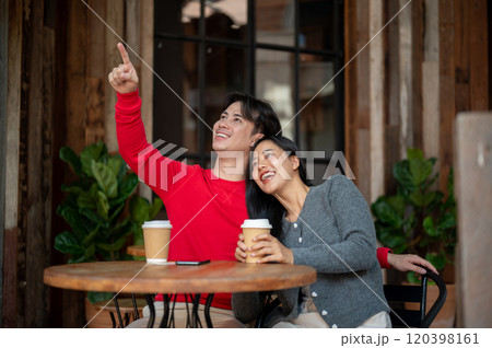 A charming Asian couple are enjoying coffee at a coffee shop while gazing the view together. 120398161