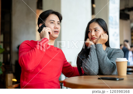 An unhappy girl feeling ignored by her boyfriend as he talks on the phone during their coffee date. An unhappy girl feeling ignored by her boyfriend as he talks on the phone during their coffee date. 120398168