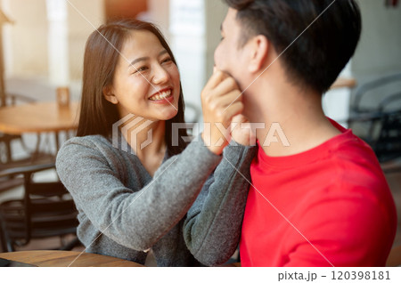 The girlfriend is playfully pinching her boyfriend's face, expressing love and cuteness. 120398181