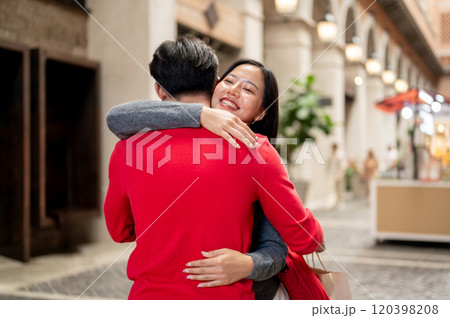 A lovely Asian couple is hugging in the middle of the city, sharing a wonderful moment together. 120398208