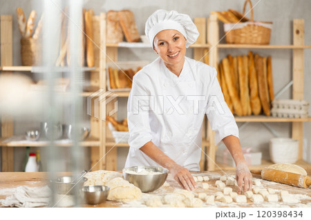 Woman works as baker in bakery, molds pies from dough, creates croissants from dough. Woman works as baker in bakery, molds pies from dough, creates croissants from dough. 120398434