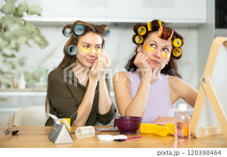 Two women curl their hair with curlers and use patches Two women curl their hair with curlers and use patches 120398464